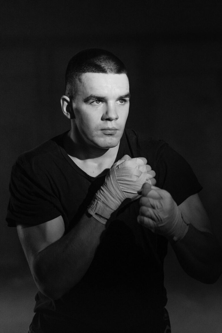 Grayscale portrait of a male fighter posing indoors, exuding focus and determination.